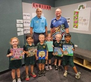 Rotarians with school children holding donated books
